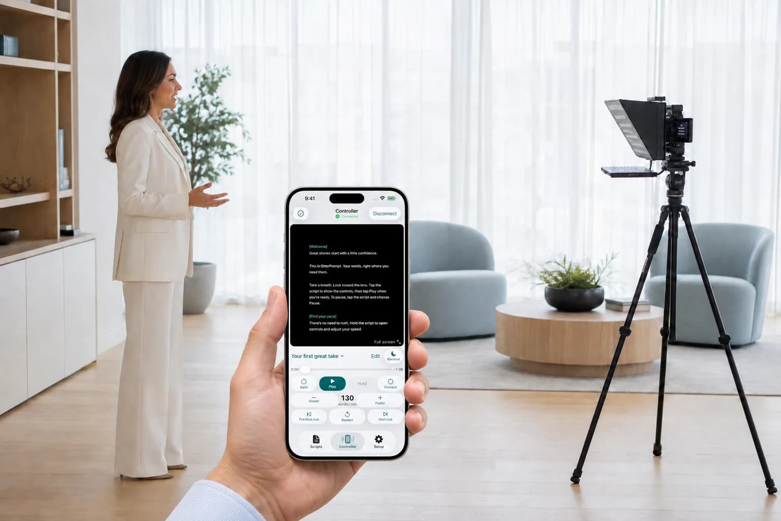 Foreground hand holding the OtterPrompt iPhone Controller, with an executive facing a compact iPad Pro teleprompter several feet away